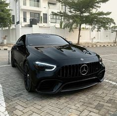 a black sports car parked in front of a white building on a brick parking lot