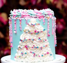 a blue and white decorated cake on a plate with pink flowers in the back ground