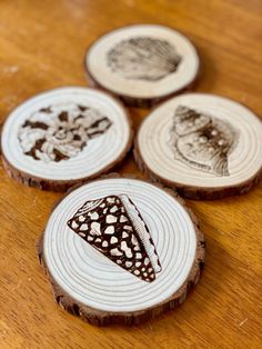 four wood slices with designs on them sitting on a table