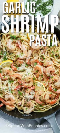 garlic shrimp pasta in a skillet with lemon wedges and parsley on the side