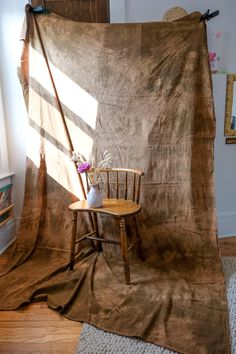 a chair sitting on top of a wooden floor in front of a brown cloth covered wall