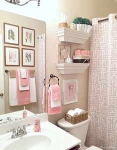 a bathroom decorated in pink and white with pictures on the wall above the shower curtain