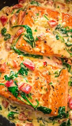 two cooked salmon fillets in a skillet with spinach and cheese on top