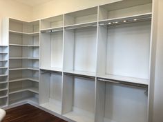 an empty walk in closet with white shelving