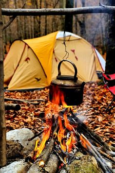 a campfire with a kettle hanging over it