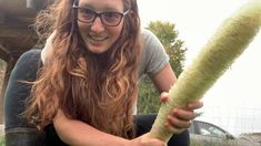 a woman is holding a large plant in her right hand and smiling at the camera