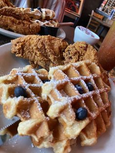 fried chicken and waffles with blueberries on a white plate at a restaurant