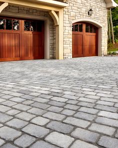 a brick driveway with two wooden garage doors