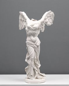 a white statue with wings on top of a table