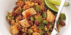 a white bowl filled with rice and beans next to a lime wedge on the side