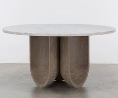 an oval marble table with two curved sections in the center, on a concrete floor