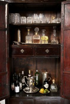 an old wooden cabinet filled with bottles and glasses