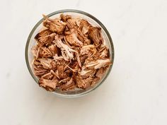 shredded meat in a glass bowl on a white surface