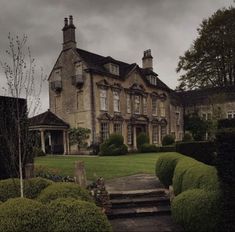 a large house sitting on top of a lush green field next to trees and bushes