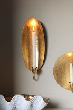 two wall sconces mounted to the side of a wall with candles in them