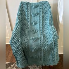 a blue knitted sweater sitting on top of a wooden chair next to a door