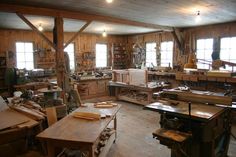 a room filled with lots of woodworking tools and workbench tables in front of windows