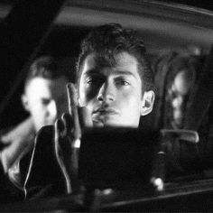 black and white photograph of two men sitting in a car looking at something on the screen