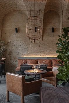 a restaurant with brick walls and leather chairs, tables and plants in the corner area