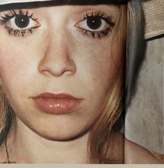 a woman wearing a hat with fake eyelashes on her face and eye lashes sticking out