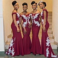 three women in red dresses standing next to each other with white flowers on the side