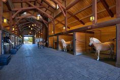 several horses are lined up in the stalls at an indoor stable with wooden walls and ceilings