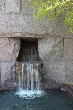 a waterfall is coming out of a hole in the side of a building