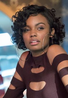 a close up of a person wearing a dress with cut out on the side and large hoop earrings