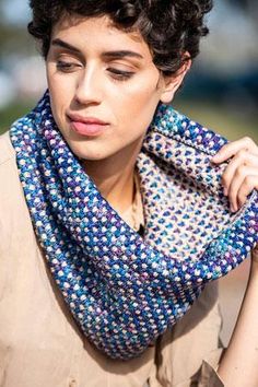 a woman with curly hair wearing a blue and white knitted cowgirl neck scarf