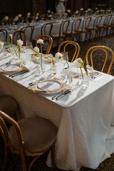 the table is set with white linens and silverware for an elegant wedding reception