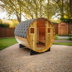 a small wooden sauna in the middle of a gravel area with grass and trees