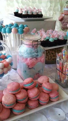 a table topped with lots of pink and blue macaroons