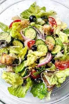 a salad with lettuce, tomatoes, cucumbers and black olives