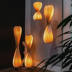 three light fixtures hanging from the side of a wall in front of a plant and door