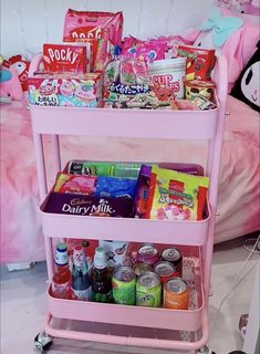 a pink cart filled with lots of food and drinks on top of a white floor