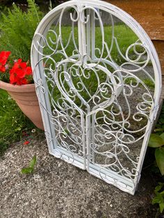 a white iron heart shaped planter sitting next to a flower pot