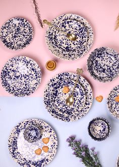 blue and white dishes with gold accents on a pink background next to lavender sprigs