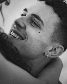 black and white photograph of a man with tattoos on his face smiling at the camera