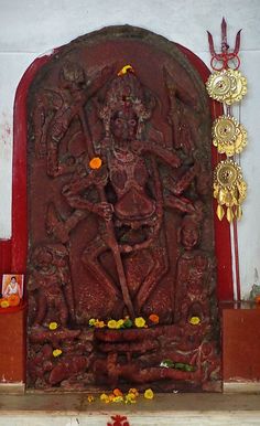 an intricately carved statue in the center of a room with flowers and decorations around it