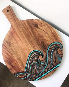 a wooden cutting board with blue and brown designs on the top, sitting on a table