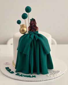 a cake with a woman in a green dress sitting on top of it and balloons