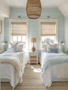 two beds in a bedroom with white linens and blue walls, one has a wicker basket hanging from the ceiling