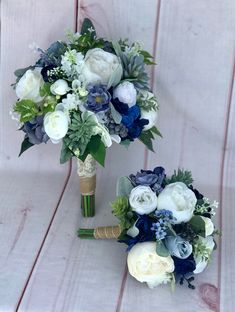 two bridal bouquets with blue and white flowers on a wooden table next to each other