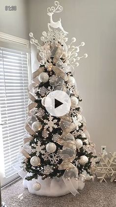 a white christmas tree decorated with silver ornaments