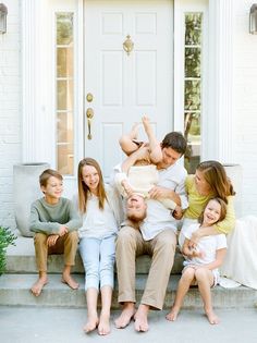 a group of people sitting on steps in front of a white door with their arms around each other