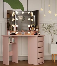 a pink vanity table with lights on it