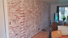 a living room with a brick wall and hard wood flooring in the middle of it