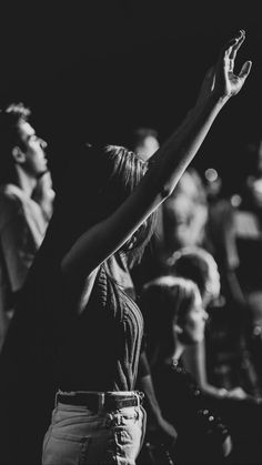 a black and white photo of a woman raising her hand in front of an audience