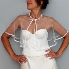 Elevate your bridal look with this enchanting sheer tulle capelet adorned with a whimsical starry trim. This lightweight, mesh bridal topper drapes elegantly over your shoulders, offering a soft, ethereal touch to any wedding gown. Tied gracefully at the neck with delicate satin ribbons, this capelet adds a touch of celestial charm, perfect for modern brides who want to shine. Whether you're seeking a unique wedding shawl, a sheer shrug, or a sophisticated bridal cover-up, this starry-trimmed capelet is the ideal accessory to enhance your special day. Neck perimeter of the model is 13.0" (34 cm). If required larger than this, feel free to contact me. Length: 13.0" (33 cm) For more similar wedding & evening cover-ups, please kindly visit https://www.etsy.com/shop/mammamiabridal?section_id=1 Sheer Capelet, Wedding Dress Capelet, Tulle Bolero, Mesh Wedding Dress, Wedding Capelet, Romantic Party, Bridal Capelet, Dress Topper, Small Stars