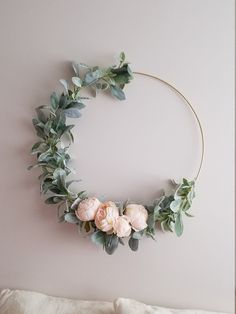 a floral wreath hanging on the wall with eucalyptus leaves and pink peonie flowers